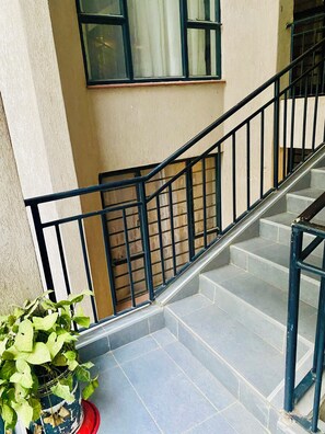 A staircase with black railings leading to an upper floor. - Veena Homes | Studio Airbnb in Nairobi (Nairobi)