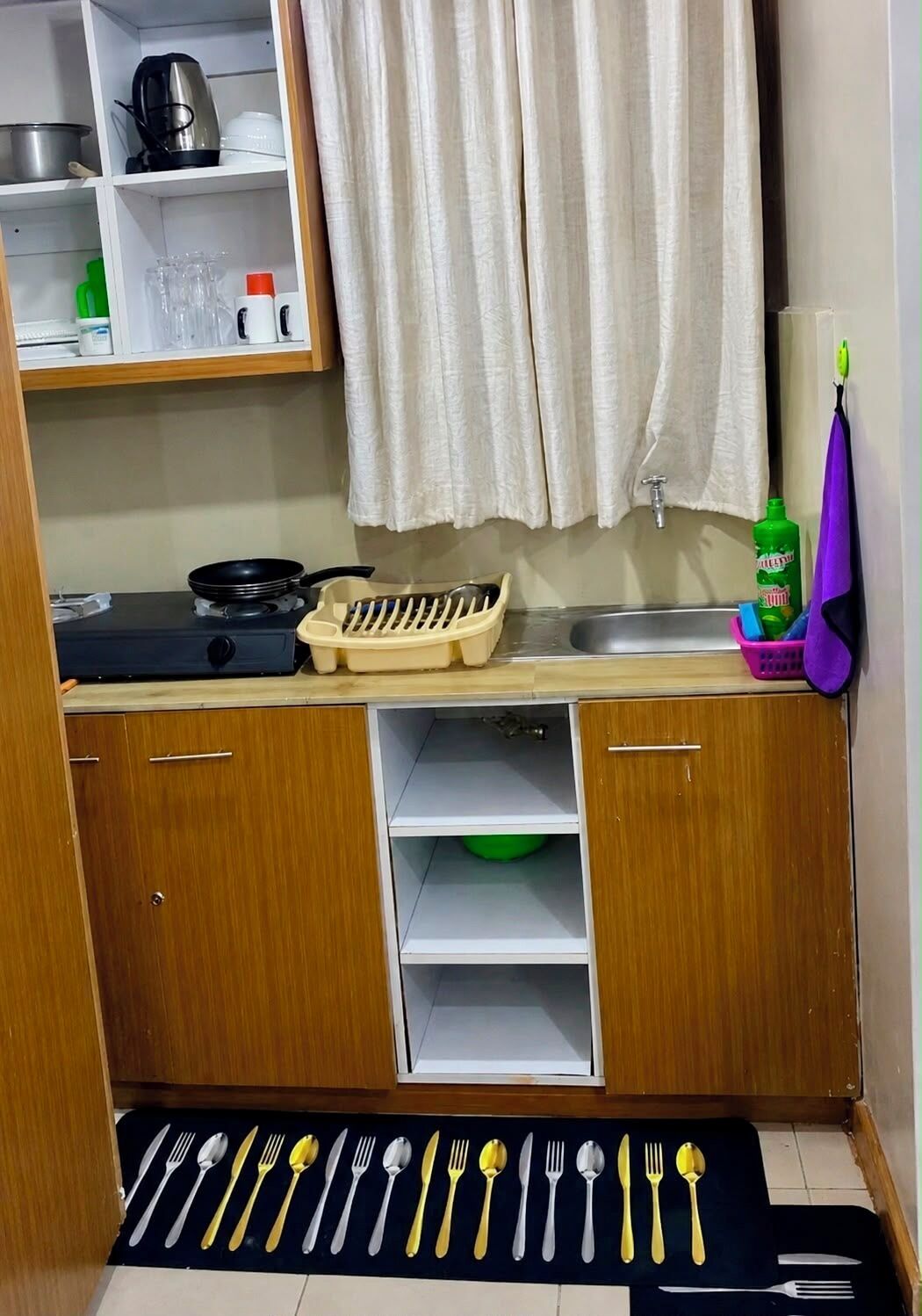 A compact kitchen with a stove, sink, and various utensils neatly arranged.