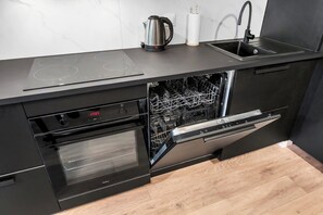 Eine moderne Küche mit eingebautem Geschirrspüler, Backofen und Wasserkocher auf der Arbeitsfläche.