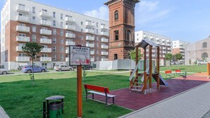 A residential area with a brick tower, a playground, and a signboard. - Elegant Apartment Near Vitsula River (Łódź)