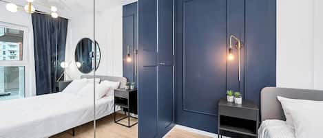 Un dormitorio moderno con un espejo grande, dos camas, mesitas de noche con lámparas y vistas al exterior.
