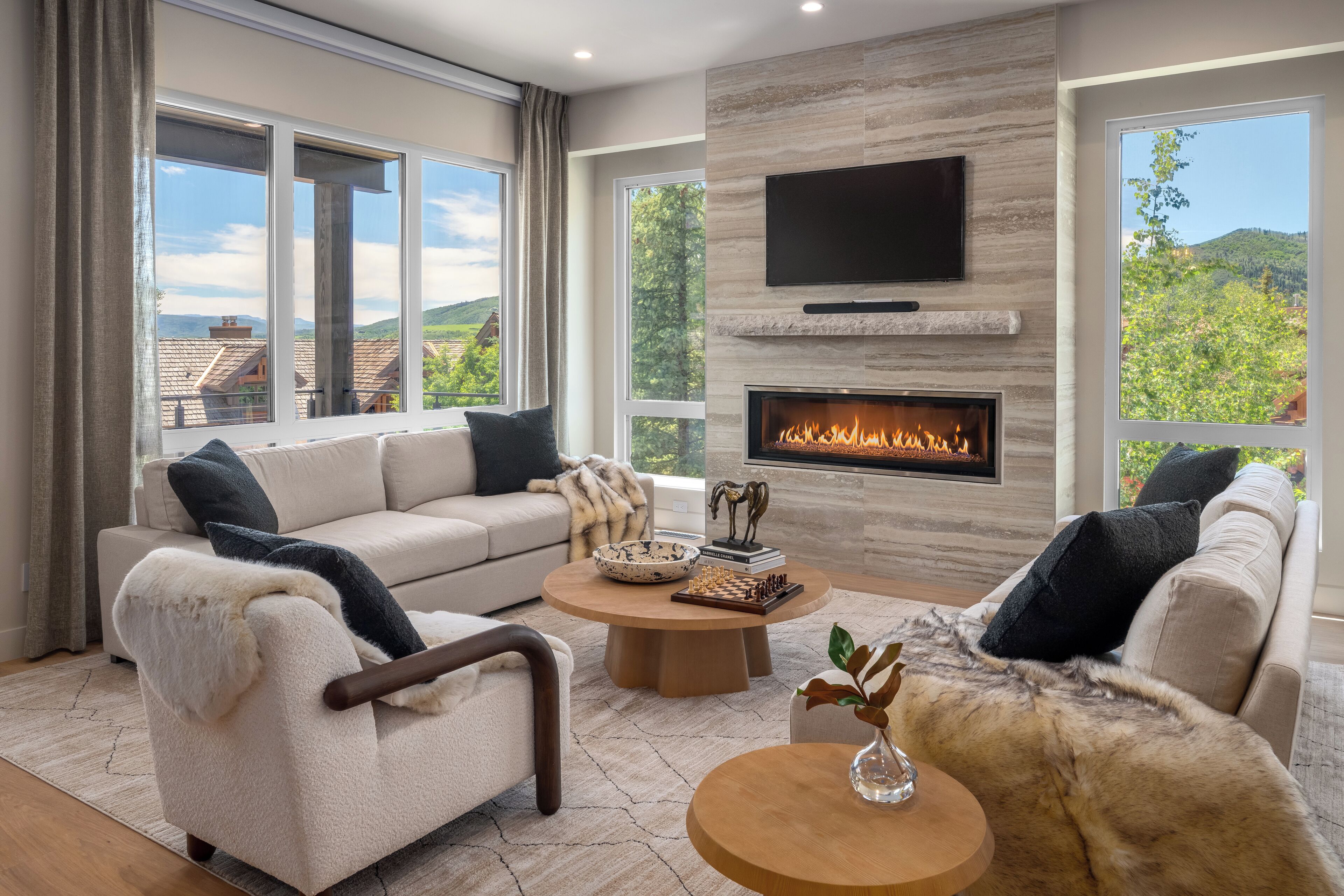 A modern living room with a fireplace, large windows, and a sofa set.