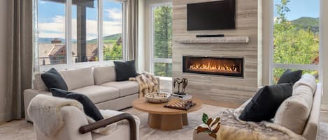 Una sala de estar moderna con chimenea, ventanas amplias y un conjunto de sofás.