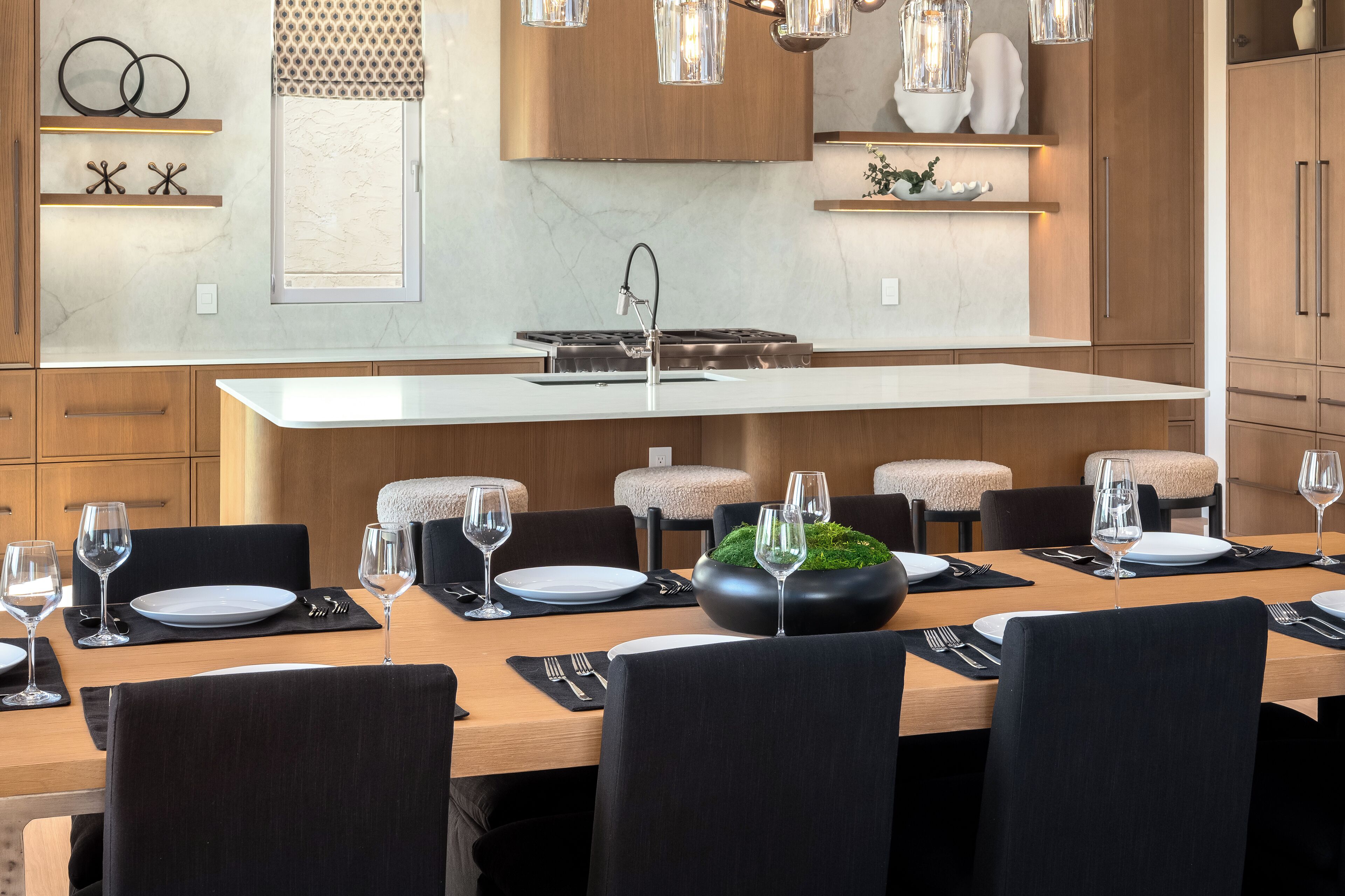 A modern kitchen with a central island, wooden cabinets, and pendant lighting.