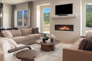 Ein modernes Wohnzimmer mit einem beigen Sofa, einem runden Couchtisch und einem Kamin.