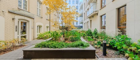 Un patio central con un jardinero, rodeado de edificios con balcones y ventanas.