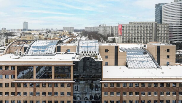 Un edificio alto con varios pisos, ventanas grandes y un tejado cubierto de nieve.