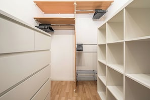 Ein begehbarer Kleiderschrank mit offenen Regalen, einem Wäscheständer aus Metall und einer Holzbalkendecke.