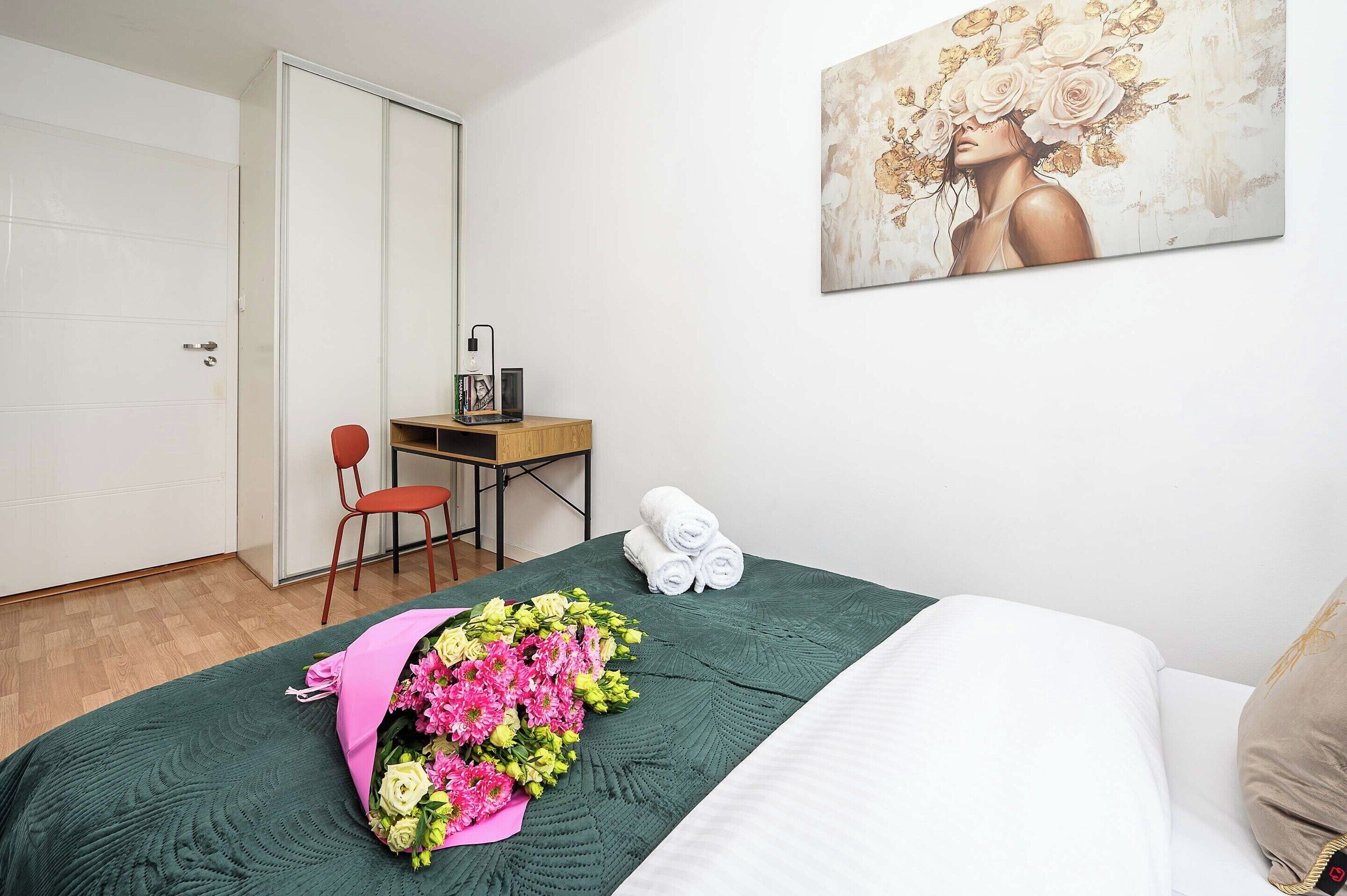 Ein Hotelzimmer mit Bett, Schreibtisch, Stuhl, Tür und einem Bild an der Wand.