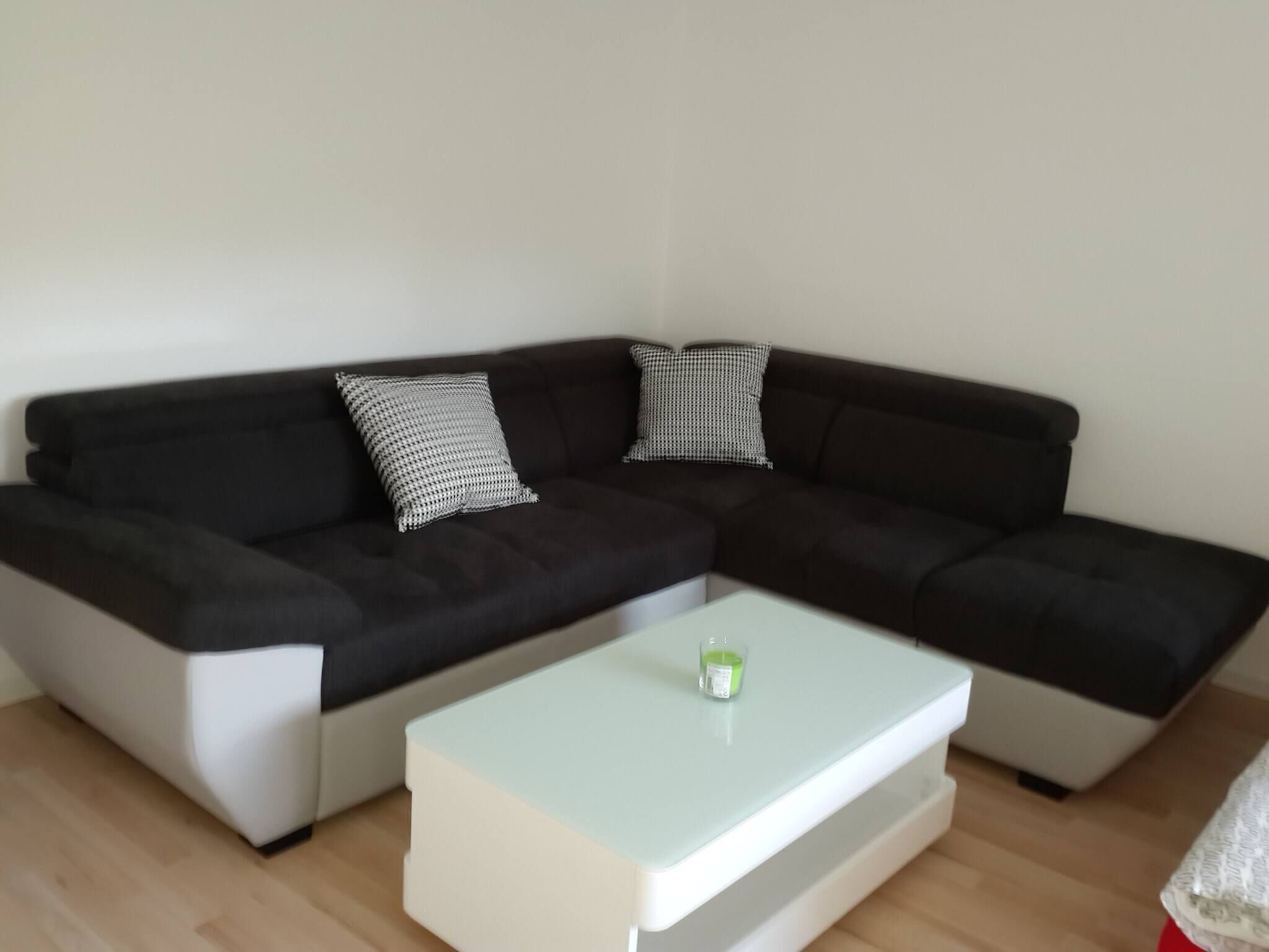 Un canapé modulable agrémenté de deux coussins à motifs, une table basse blanche et un petit objet vert posé sur la table.