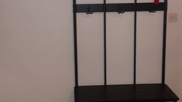 A black metal rack with hooks and a bench against a plain wall.