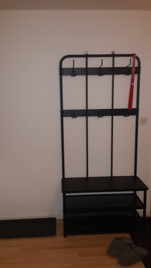 A black metal rack with hooks and a bench against a plain wall. - Sesvenna Apartment Davos (Davos)