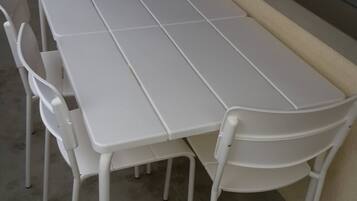 A white table with four chairs, positioned against a wall with a window.