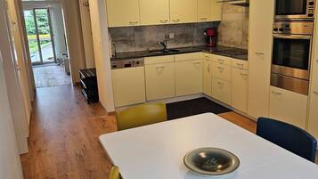 A modern kitchen with a dining area, featuring a built-in oven, microwave, and a coffee maker.