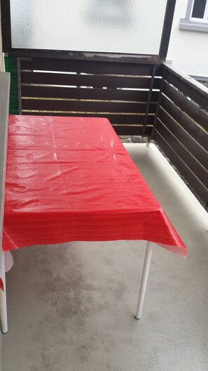 Una mesa roja con patas blancas en un balcón.