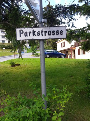 Señal de 'Parkstrasse' con un automóvil azul estacionado al fondo.