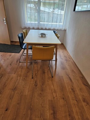 Un comedor con mesa, sillas y ventana con vistas a edificios.