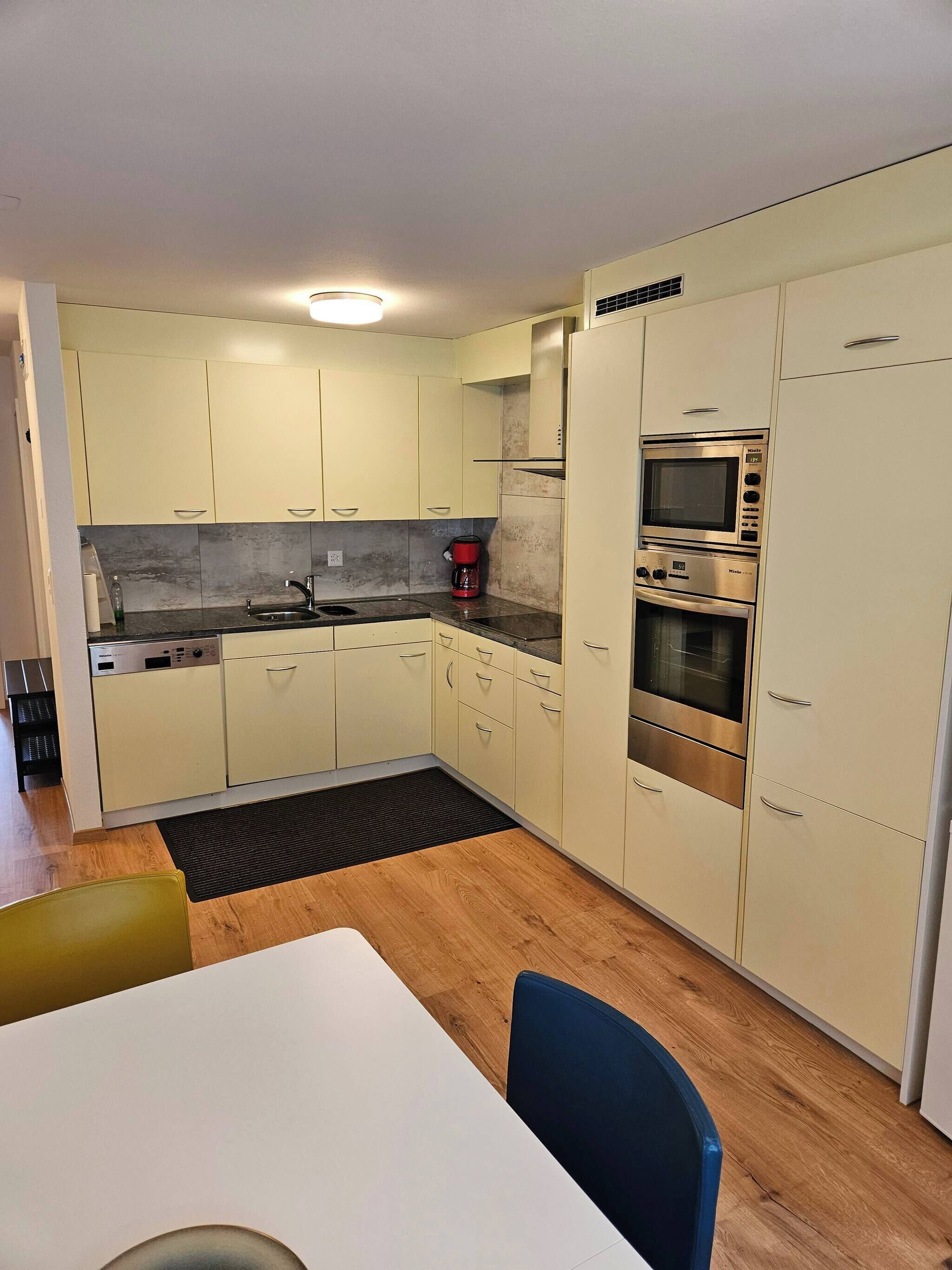 A compact kitchen with a sink, a coffee maker, and a double oven.