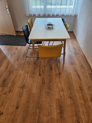 Uma sala de jantar com uma mesa branca, cadeiras amarelas e uma cadeira preta.