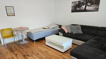 A compact living space with a bed, a sofa, a small table, and a chair.