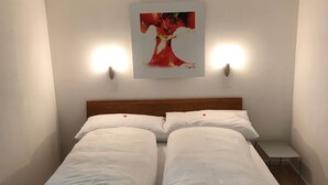 A double bed with white linens, a wooden headboard, and two wall-mounted lights. - Parkareal Davos Apartment (Davos)