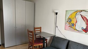 A living room with a sofa, a dining table with chairs, a small wooden table, a floor lamp, and a closet with a sliding door. - Parkareal Davos Apartment (Davos)
