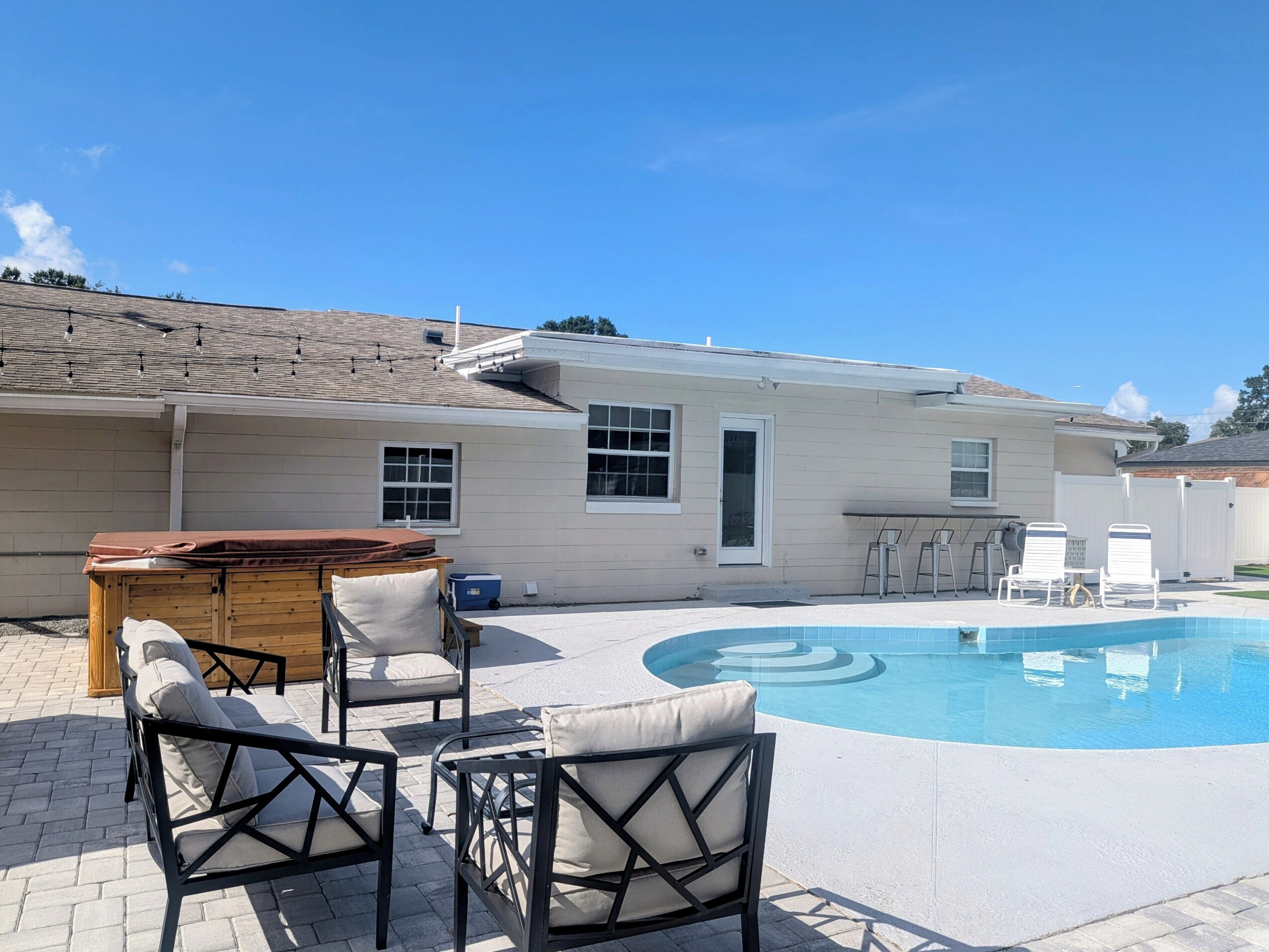 A residential property with a swimming pool, outdoor seating, and a covered hot tub.