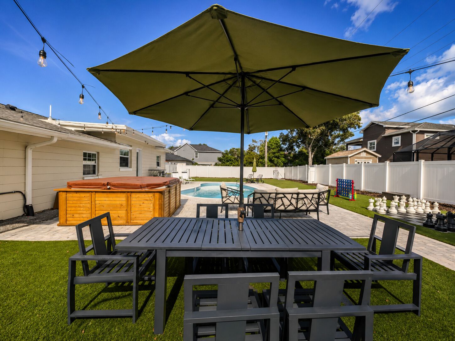 Ein Garten mit Whirlpool, Pool und einer Terrasse mit Stühlen.