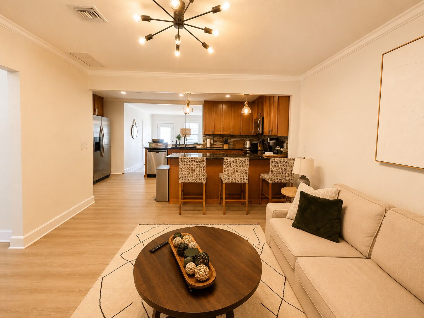 A modern living room with a wooden coffee table, a sofa, and a kitchen area in the background.