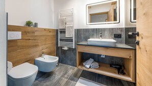 A modern bathroom with a bidet, a sink, and a mirror.