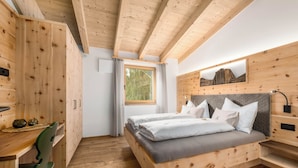 A wooden room with a bed, a desk, and a chair.