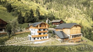 A cluster of wooden buildings with multiple floors, surrounded by a mountainous landscape.