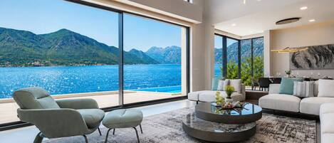 A modern living room with a large window overlooking a mountainous coastline.