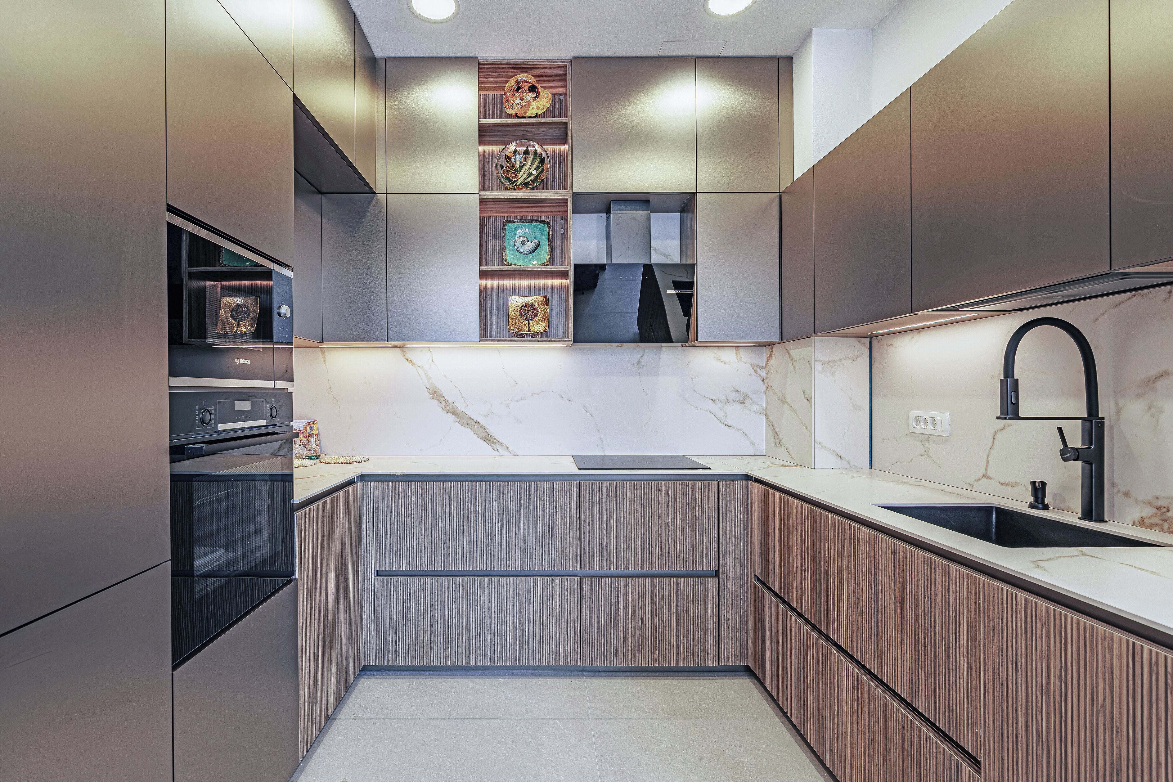 A modern kitchen with built-in appliances, a marble countertop, and a sleek faucet.