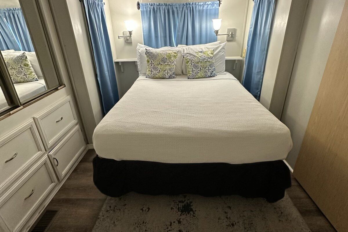 A bedroom with a bed, two bedside tables, a dresser, and a mirror.