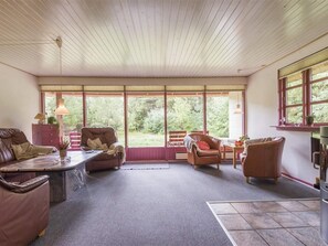 Ein geräumiger Raum mit großem Fenster, einem Sofa, einem Sessel und einem Tisch.