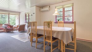 A dining area with a wooden table and chairs, a window with a view of greenery, and a ceiling with wooden beams. - 5 Star Holiday Home in Blavand (Blavand)