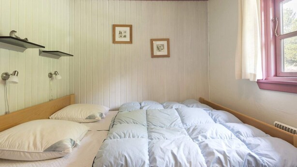 A bedroom with a bed, two wall-mounted lamps, and two framed pictures. - 5 Star Holiday Home in Blavand (Blavand)