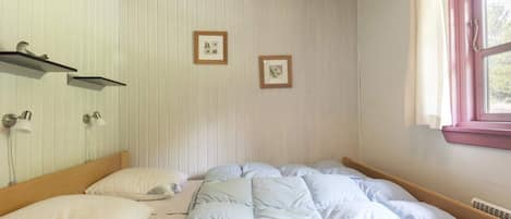 A bedroom with a bed, two wall-mounted lamps, and two framed pictures.