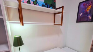 Ein Zimmer mit einem Etagenbett, einem Schreibtisch mit Lampe, einem Stuhl und zwei gerahmten Bildern an der Wand.