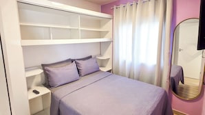 Ein Schlafzimmer mit Bett, Kleiderschrank, Spiegel und Deckenleuchte.