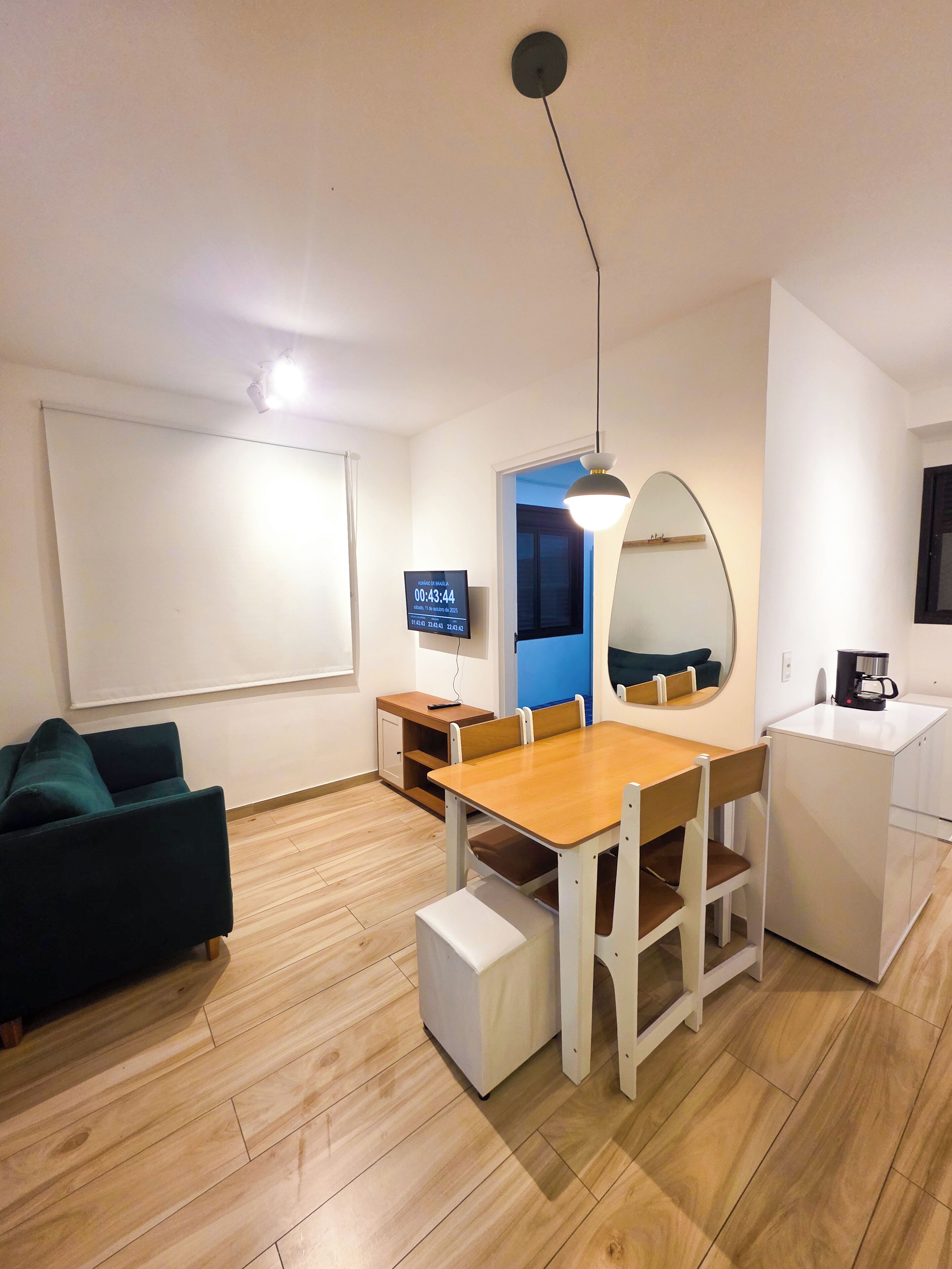 Ett modernt vardagsrum med en matplats, en platt-TV, en kaffemaskin och en stor spegel.