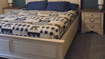 A bedroom with a bed, nightstands, a dresser, and a ceiling fan.