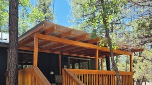 A wooden cabin with a covered porch, wooden steps, and a view of the surrounding forest. - Husky Bear Retreat - Beautiful house in the tall pines of Pinetop Lakeside (Pinetop-Lakeside)