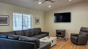 A living room with a sectional sofa, a fireplace, a television, and a ceiling fan.