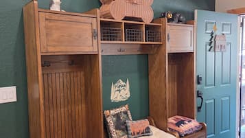 A cabin-style room with a wooden bench, a welcome sign, and a door with a keyhole.