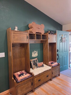 A cabin-style room with a wooden bench, a welcome sign, and a door with a keyhole.