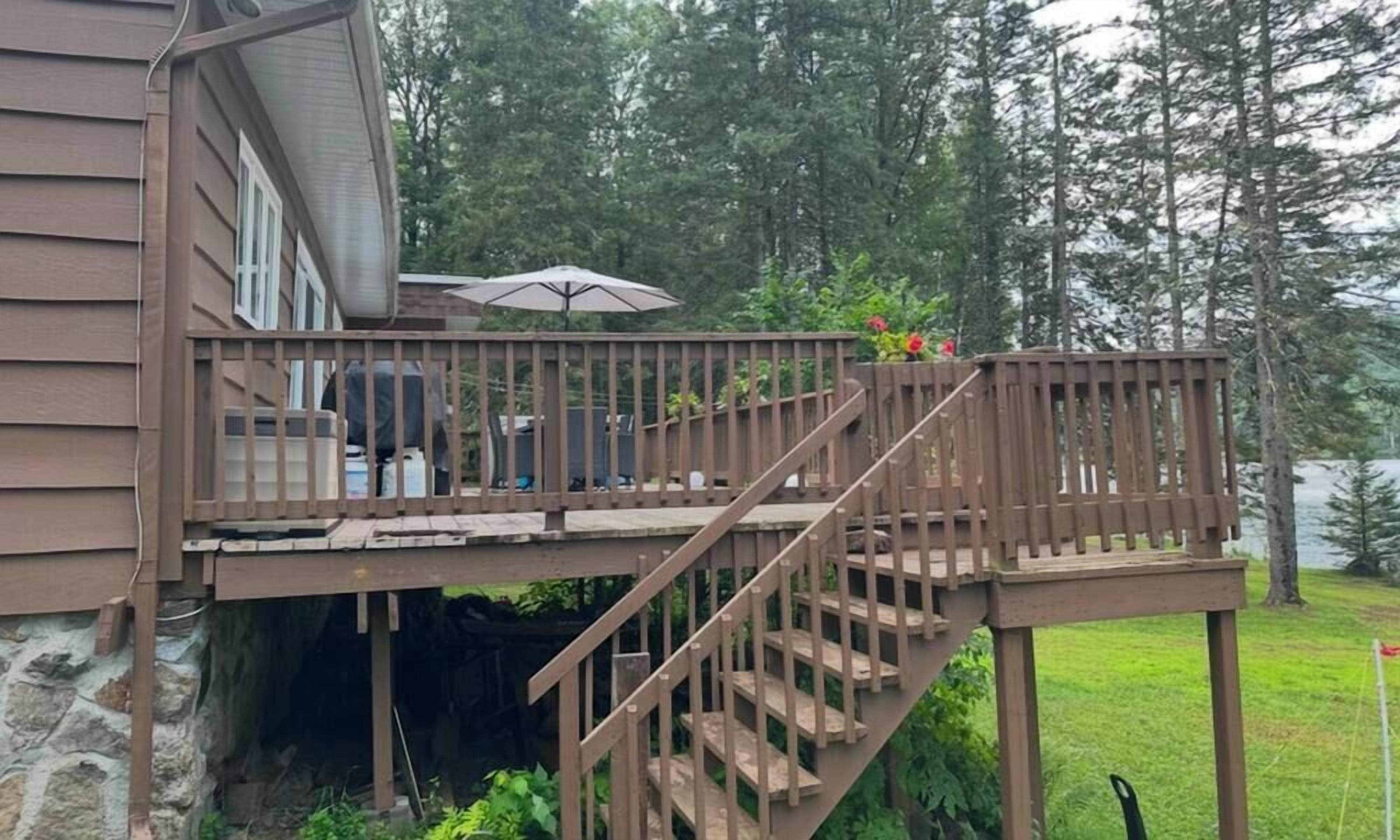 A wooden deck with a staircase leading to a covered area with outdoor furniture.