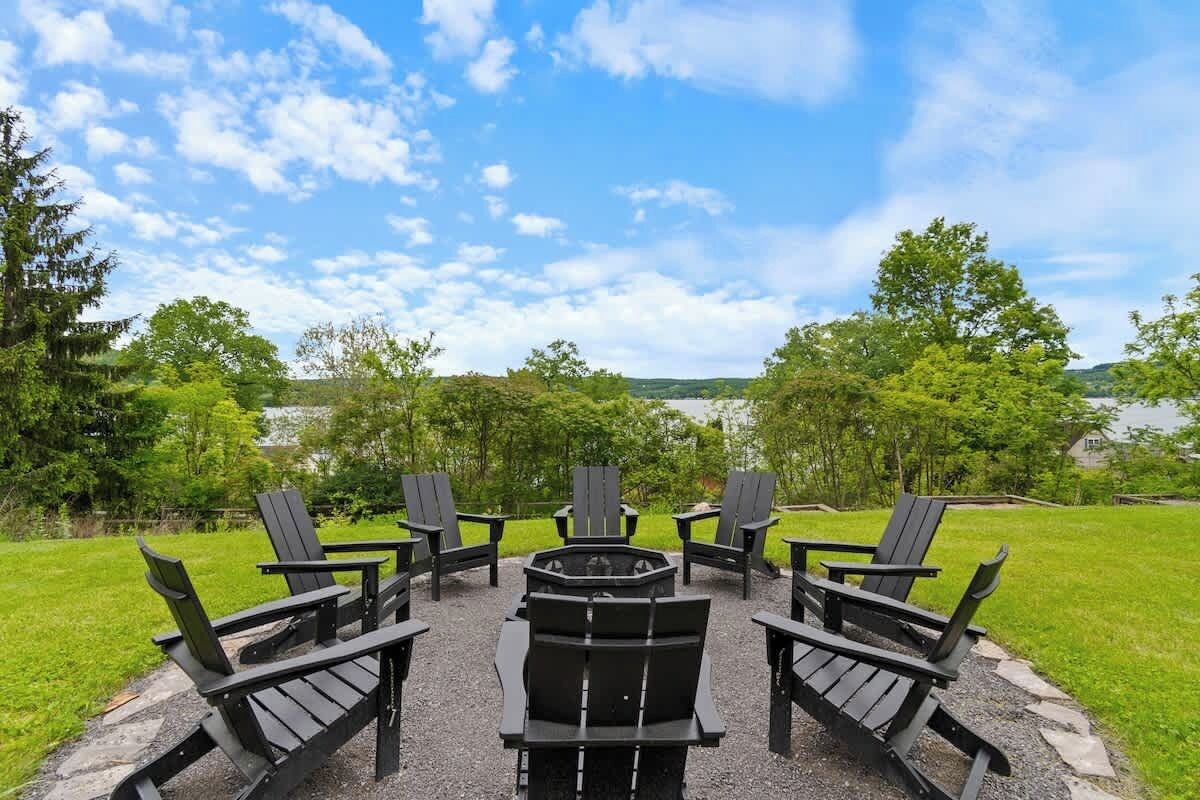 A circular outdoor seating area with Adirondack chairs and a central fire pit.