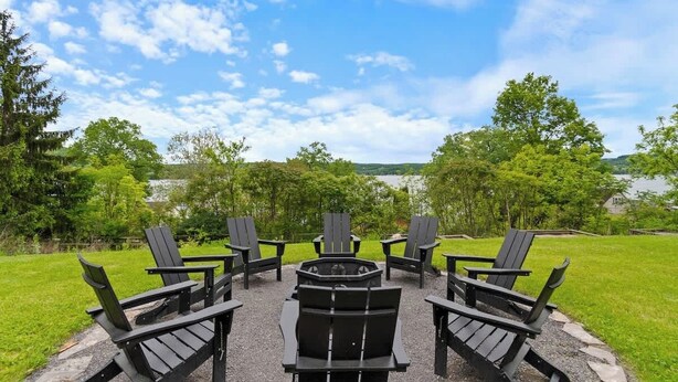 A circular outdoor seating area with Adirondack chairs and a central fire pit. - Lakeview House: Hot Tub, Speakeasy, Firepit, Gameroom (Hammondsport)